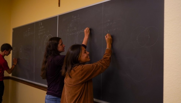 Three students practice on different parts of the blackboard