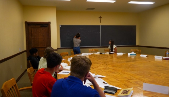 A student practices their presentation at the board