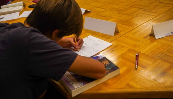 Closeup over the shoulder of a student to his notebook, in which Prop 1 is being written out