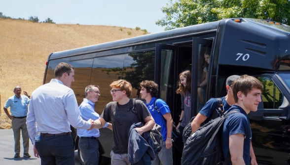 Admissions staff greets the summer programmers as they emerge from a black van
