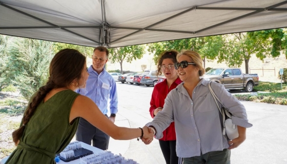 A recent graduate shakes hands with a summer programmer and her mother