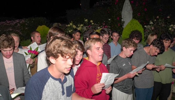 The front line of men, singing with lyrics in hand