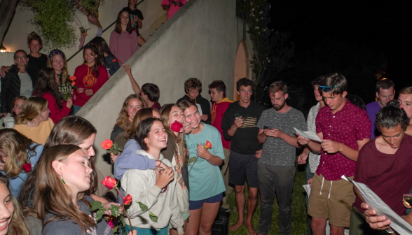 The women in the front, flowers in hand, watch the men sing