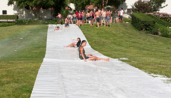 Students slide down the slip'n'slide, some headfirst, some sitting up