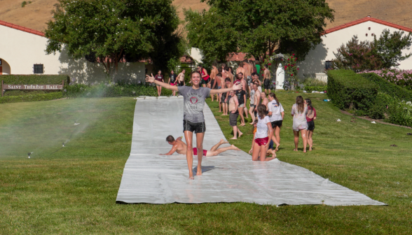 A student rises triumphantly from the end of the slide