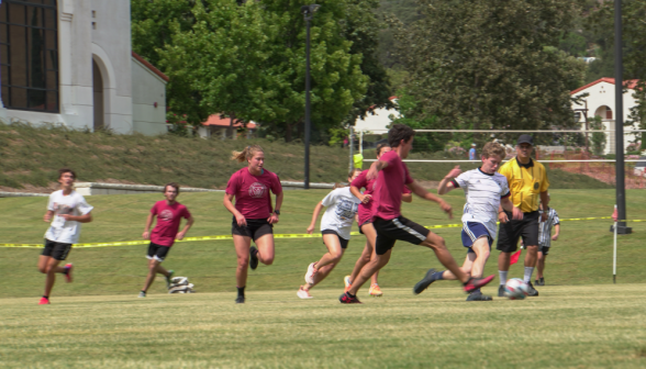 One student defending the ball, while a prefect attempts to steal it