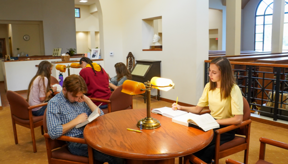 Two students at a table overlooking the main stacks