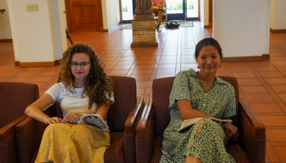 Two students in the armchairs smile for the camera