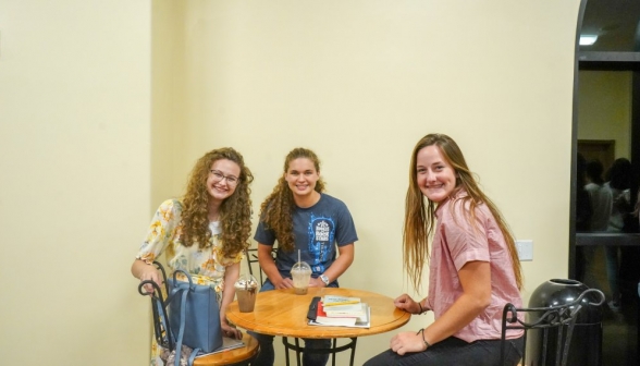 Three pose around a coffee table