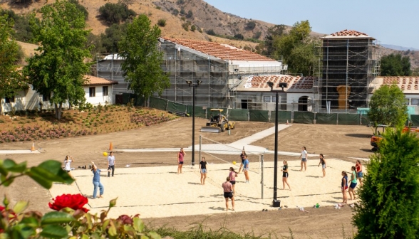 View of the volleyball game, with the JP2 Athletic Center, wreathed in scaffolding, visible in the background