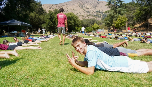 Students lying down in rows on the grass into the distance