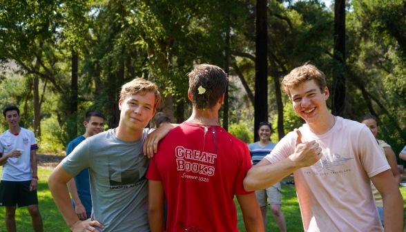 One student is plastered with egg. His friends smile at the camera and give a thumbs-up