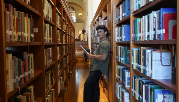 A student between two rows of bookshelves