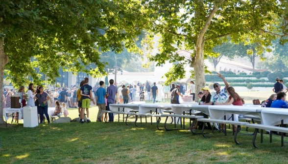 Crowds of summer programmers and families gather behind long trestle tables for the BBQ