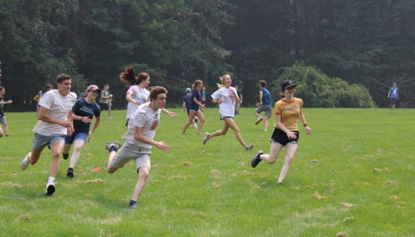 A group of students running toward something out of frame