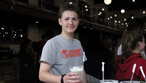 A student in a "Stark Industries" T-shirt poses for the camera with their soda