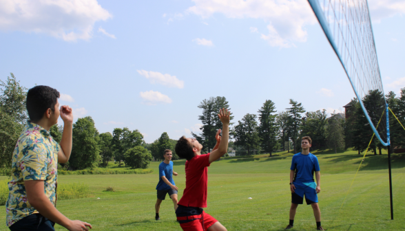 At the volleyball net, the setter prepares for an incoming shot