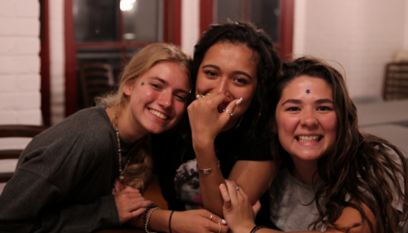 Three girls pose for a photo, with star stamps on their faces
