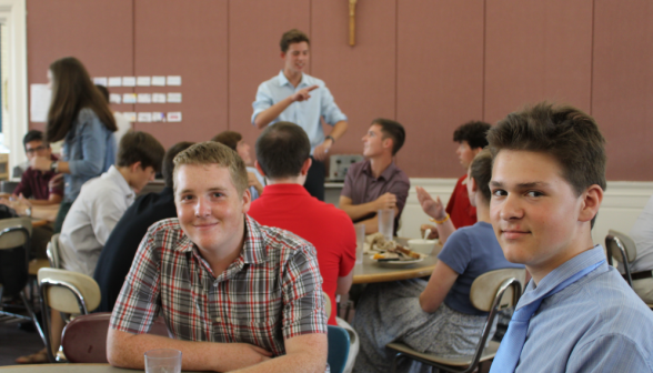 Another pair of students seated at a table, smiling for the camera