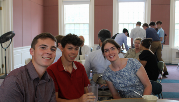 Two students with a staff member at a table
