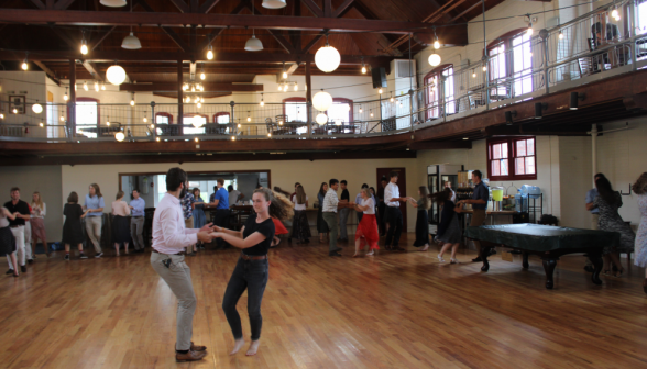 Isaac Cross, in the center of the room, demonstrates dance moves with Niamh McCann