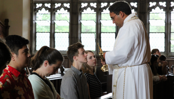 Fr. Miguel holds out the relic for another student