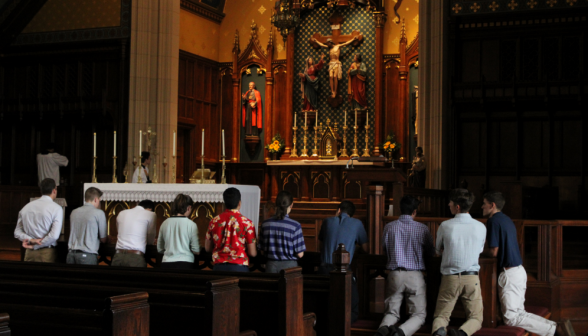 Students kneel at the rail, with the newly-painted sanctuary visible in the background