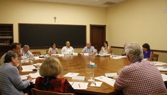 The attendees, gathered around the seminar table, discuss the text