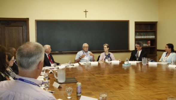 Long shot of Dr. McLean at the head of the table, mid-explanation