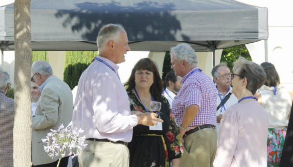 Attendees chatting outdoors, with a glass of wine