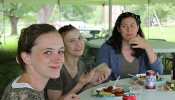 Two students and a staff member pose with their food at a table