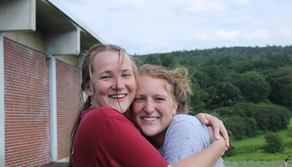 Close-up: two women prefects hug afront the gym