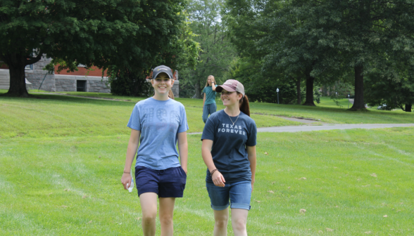 Two walk down past Stone Hall toward the softball field