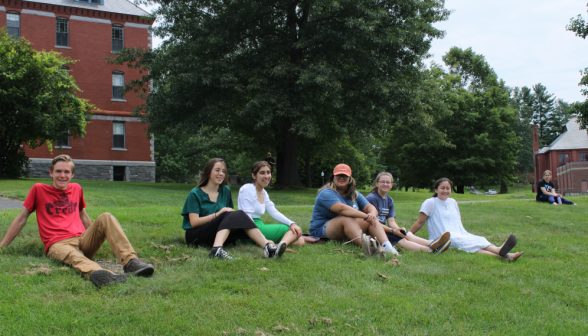 Seven students sitting on the grass, watching the game