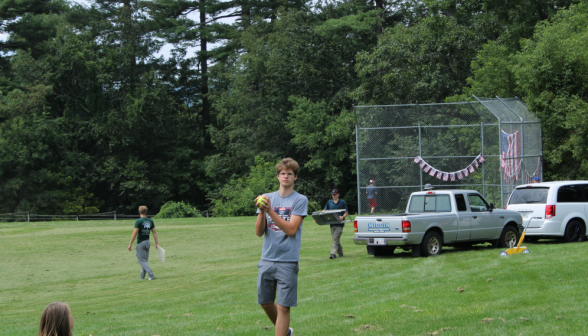 A student holding the ball, with the bunting-decorated backstop in the distance