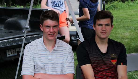 Two students seated beside the back of a pickup truck