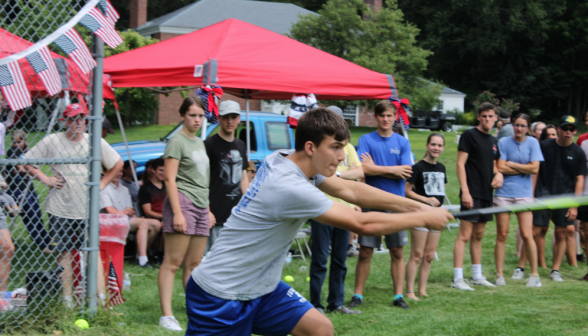 A students swings at the ball, afront a row of spectators