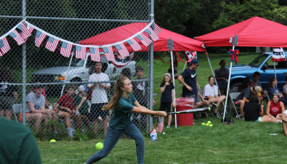 A student swings for the ball, afront the bunting