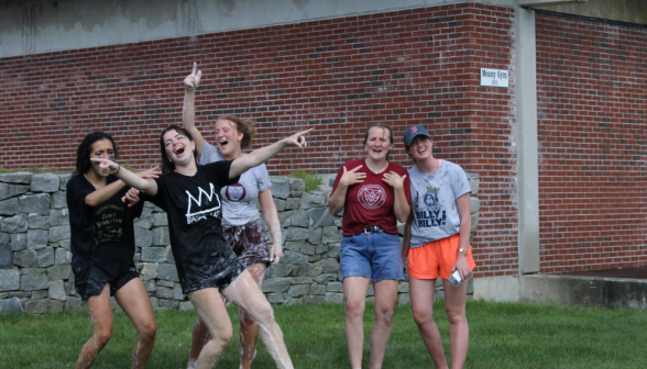 Five girls cheering enthusiastically outside the Meany Gym