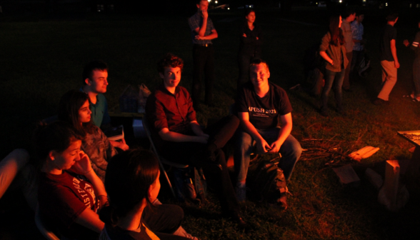 Five students in a small group on one side of the fire