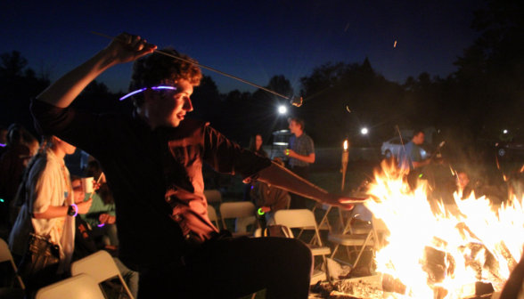 A student assumes what appears to be a "Firebender" pose with the bonfire and a marshmallow on a stick