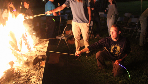 Standing at various distances from the blaze, students roast marshmallows