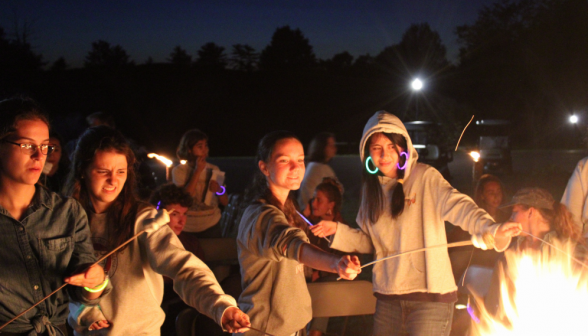 Four cautiously attempting to roast their marshmallows without themselves getting burnt