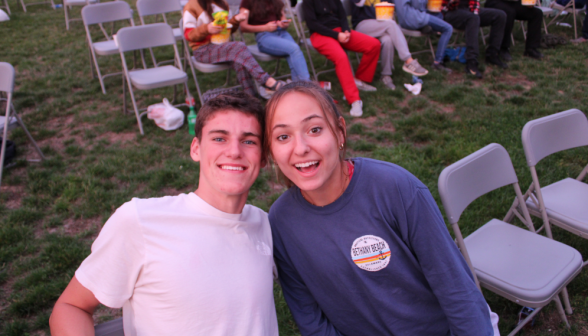 Two students pose for a photo near the chairs as the sun sets