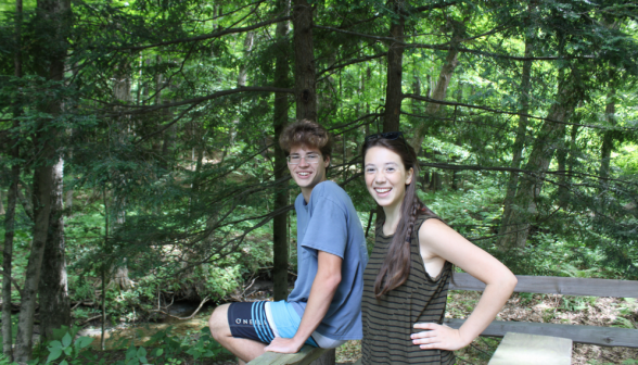 Two students seated on a bench at the river