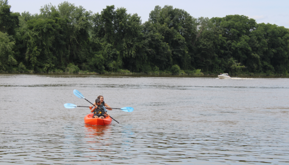 Two in a kayak, with a motorboat visible in the distance