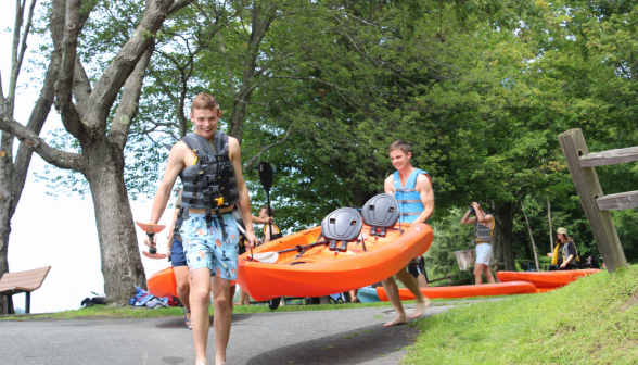 Two students carry a kayak down to the water