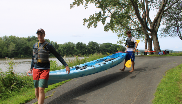 Another pair of students carry a blue kayak