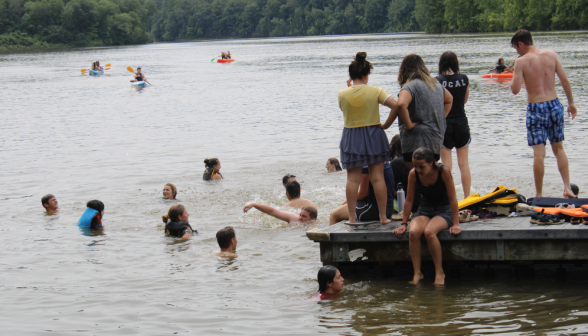 Several students splashing about in the water near the pier