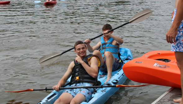 Two in a blue kayak pass by the pier